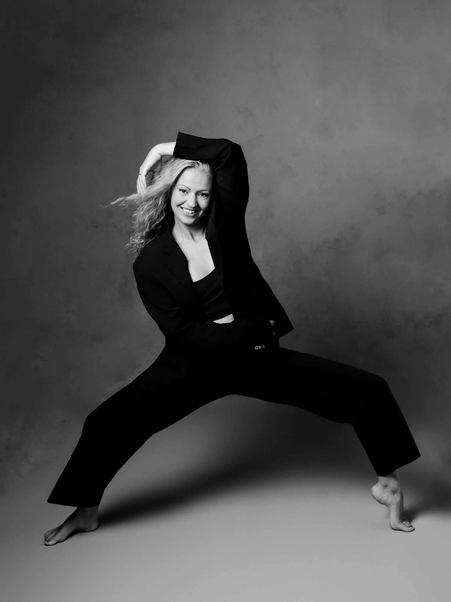 Boss Babe Noralie posing in a black suit with arm raised