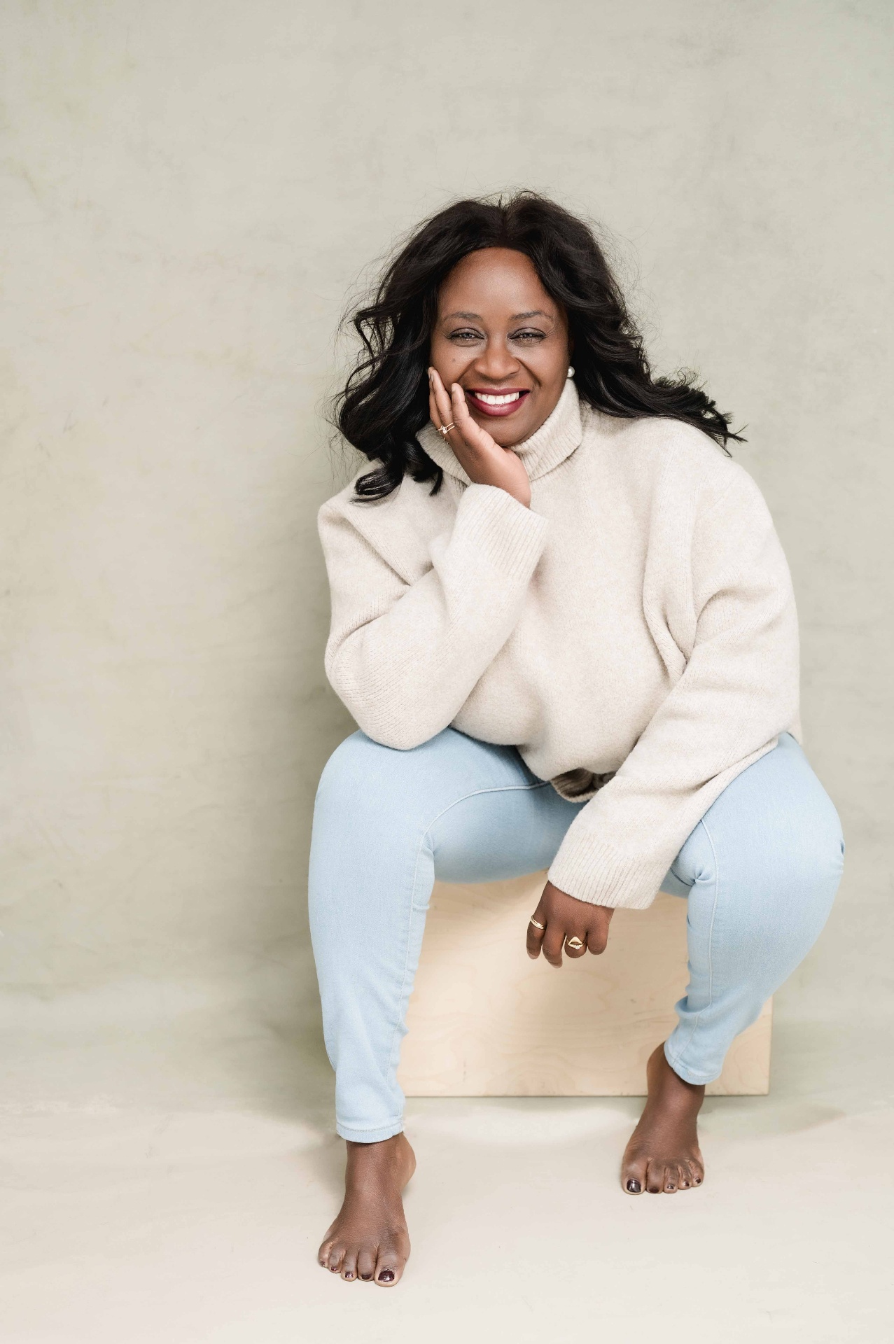 Boss Babe Loini smiling in a cream sweater and light jeans